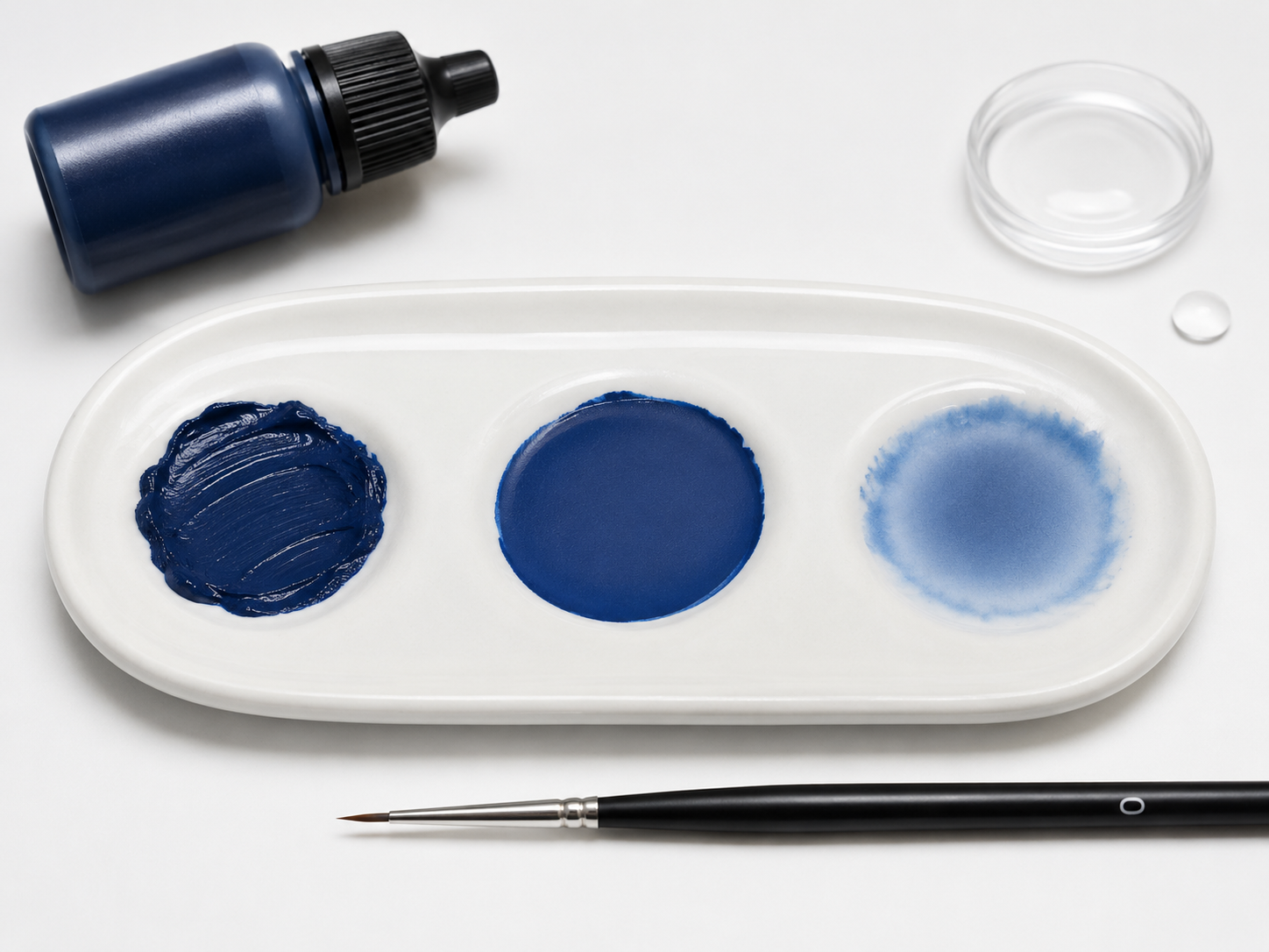 Drei Proben dunkelblauer Farbe mit unterschiedlicher Verdünnung auf einer Palette